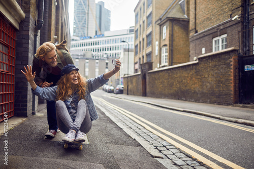 Playful couple enjoying a ride on a skateboard in an urban alley photo