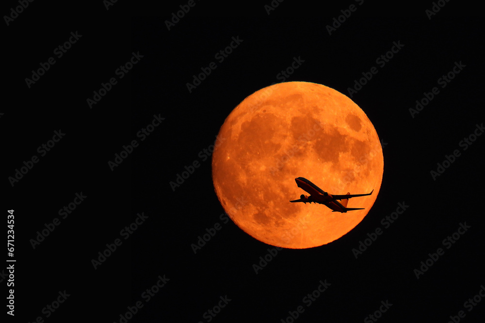 flying plane against the background of the red moon