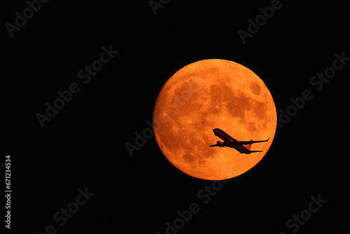 flying plane against the background of the red moon