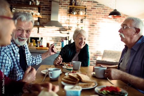 Group of senior friends having breakfast together in the kitchen