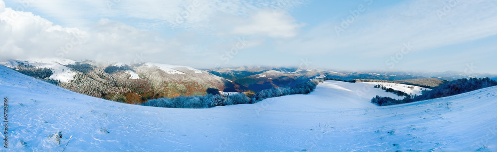 October mountain beech forest edge with first winter snow and last autumn colourful foliage on far mountainside. Four shots stitch image.