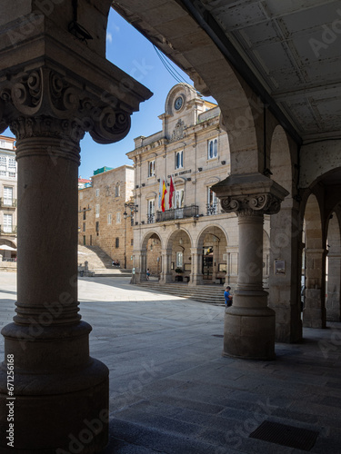 Vistas de la plaza porticada del ayuntamiento de Orense desde los arcos con columnas adornadas en un día soleado de verano de 2021, España.
