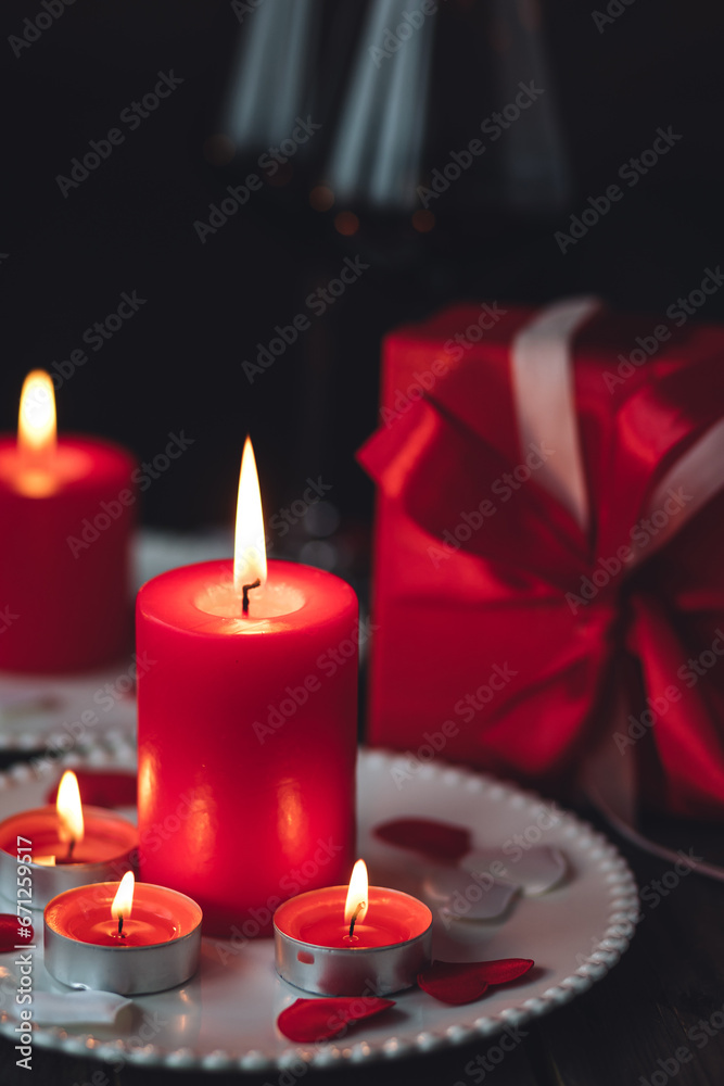 Saint Valentine's Day celebration. Red burning candles, hearts, gift box, postcard on dark wooden background. Happy holiday . Table decor for festive dinner, romantic atmosphere Saint Valentine's Day celebration. Red burning candles, hearts, gift box, postcard on dark wooden background. Happy holiday . Table decor for festive dinner, romantic atmosphere