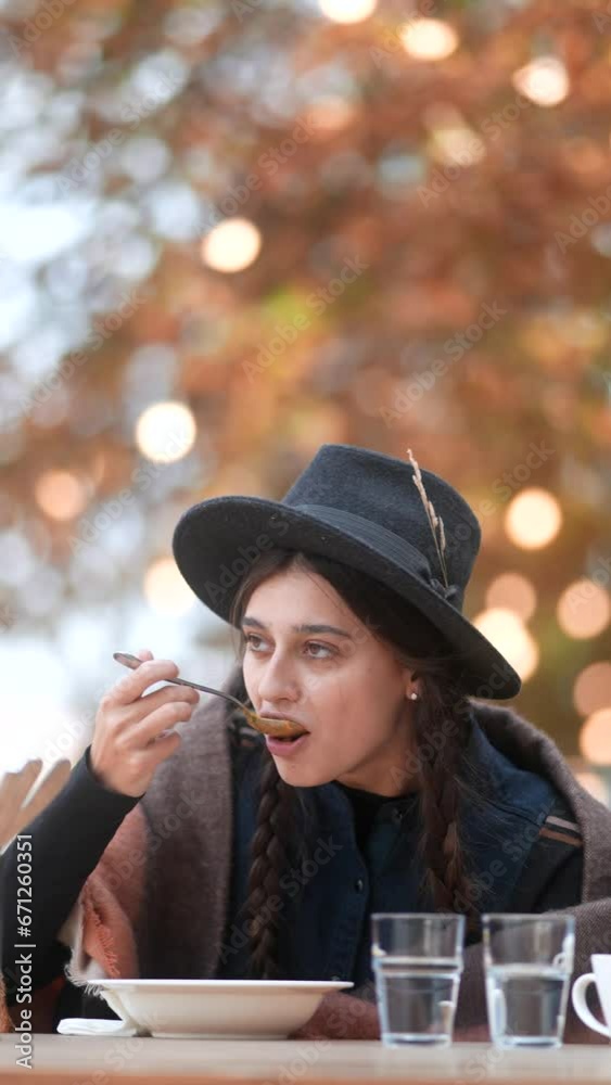 A lively young lady, dressed for autumn, enjoys her meal on the outdoor terrace. A lively young lady, dressed for autumn, enjoys her meal on the outdoor terrace.