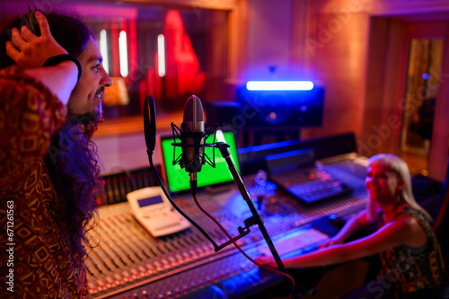 Profile of a singer recording a song in a music studio.