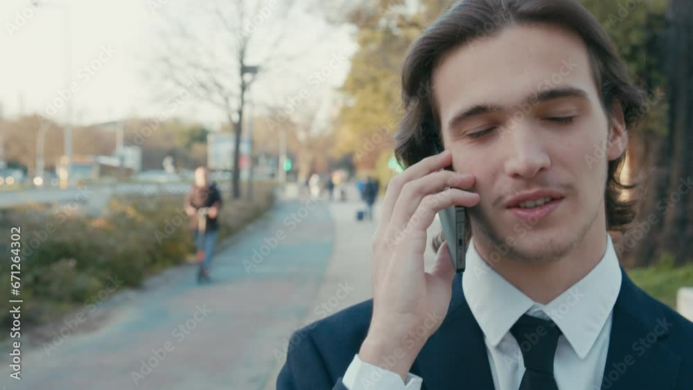 A smiling businessman in the city talking on a cell phone. Man in a business suit is walking down the street and talking on the phone. A young man in a suit talking on a smartphone, slow motion. A smiling businessman in the city talking on a cell phone. Man in a business suit is walking down the street and talking on the phone. A young man in a suit talking on a smartphone, slow motion.