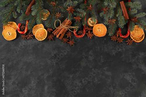 Christmas background with winter traditional spices to improve immunity during the cold period. Star anise, cinnamon and dried oranges and tangerines on a dark background with fir branches. photo