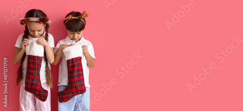 Cute little children with Christmas socks on pink background with space for text