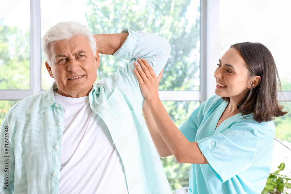 Obraz premium Female physiotherapist working with senior patient in rehabilitation center