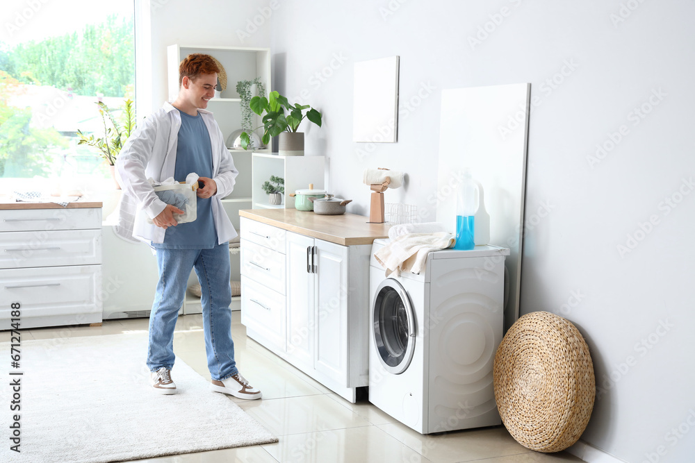 Obraz premium Young man with laundry basket near washing machine