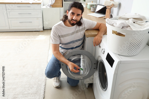 Young man putting laundry c...