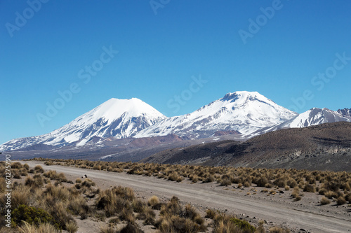 Image shows sand road and Parinacota and Pomerape volcano photo