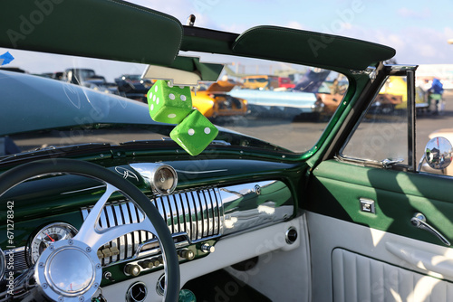 Fototapeta Naklejka Na Ścianę i Meble -  green fuzzy dice hanging from the mirror of a vintage muscle car