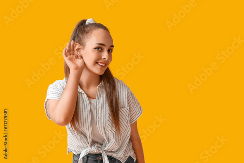 Canvastavla Teenage girl trying to hear something on yellow background