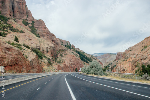 Scenic highway among red canyons on a sunny autumn day. Beautiful landscape with high red mountains and green bushes. Echo Canyon, Utah, USA in fall