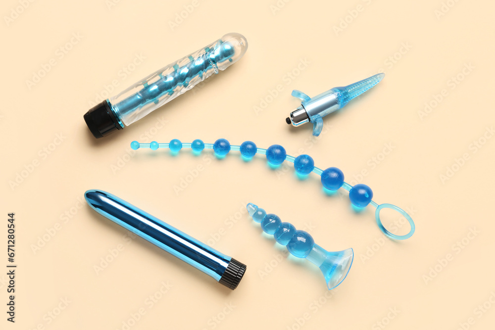 Vibrators and anal plugs from sex shop on beige background