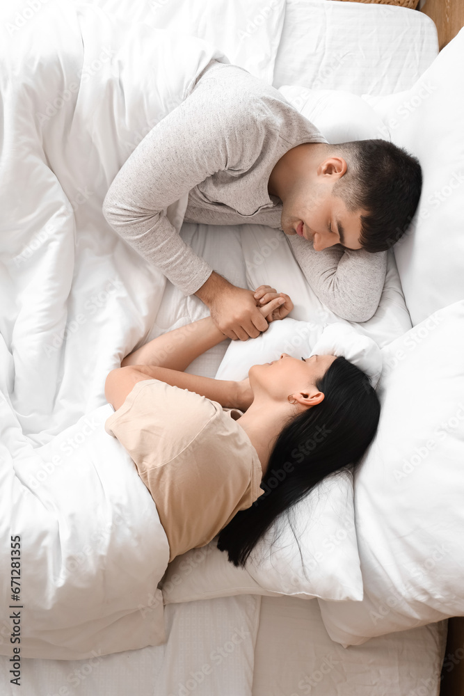 Fototapeta premium Young couple sleeping in bedroom, top view