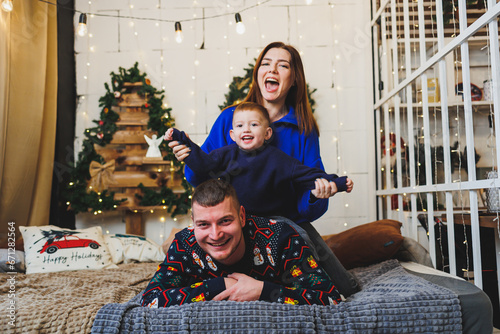 A happy family couple with a child in New Year locations. New Year's festive mood in the family circle. Christmas decorations in the bedroom. New Year. Christmas decorations at home