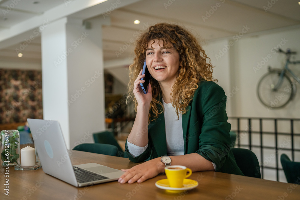 Woman use smartphone make a call talk while work on laptop from cafe Woman use smartphone make a call talk while work on laptop from cafe