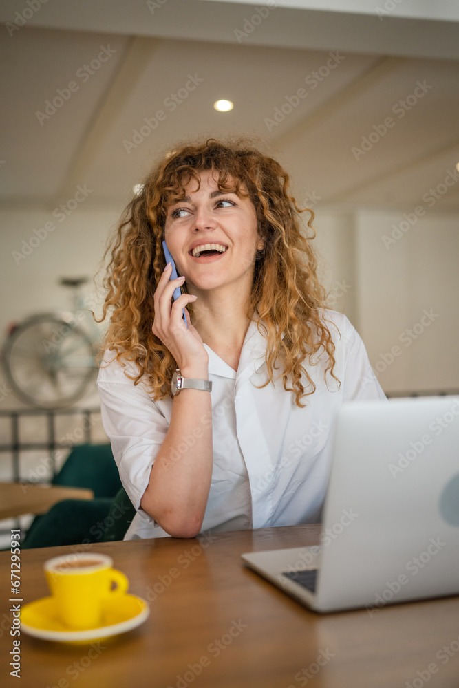 Woman use smartphone make a call talk while work on laptop from cafe Woman use smartphone make a call talk while work on laptop from cafe