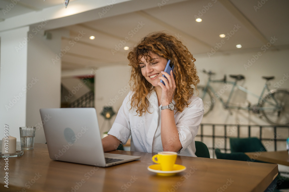 Woman use smartphone make a call talk while work on laptop from cafe Woman use smartphone make a call talk while work on laptop from cafe