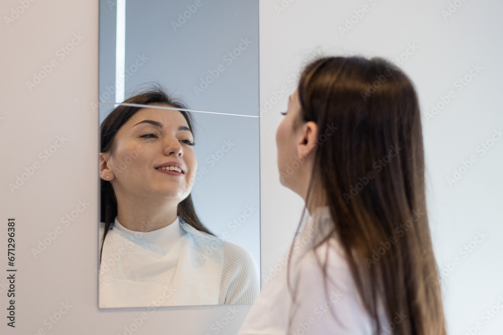 Young girl looks bleached teeth in the mirror in dentistry. Young girl looks bleached teeth in the mirror in dentistry.