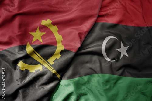 big waving national colorful flag of angola and national flag of libya .