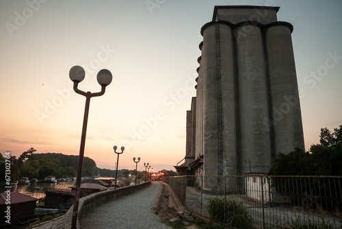 Panorama of the Tamis river, on Pancevo Waterfront in the center of the city, during a warm summer sunset. Iconic silos are visible in front. Pancevo, Serbia, is one of the biggest cities of banat. #671302764
