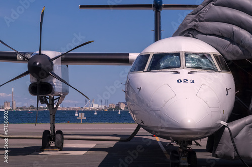 Photography Front view of white modern turboprop airliner with close-up of pointed nose with cockpit windows, black six-bladed propeller and engine nacelles, landing gear, part of wing and large T-tail
