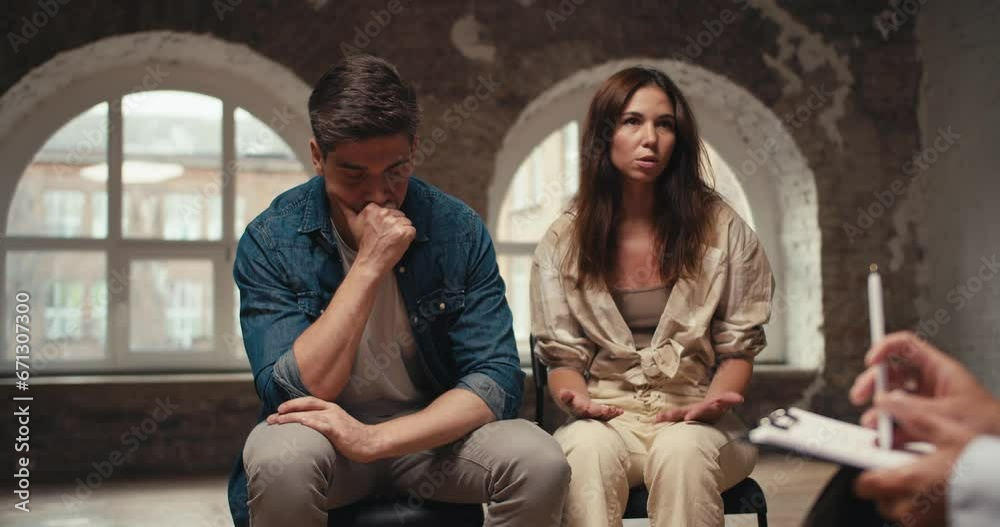 A tired brunette girl talks about her problems of living in a couple with a brunette guy who is thoughtful and holds his hand to his mouth during therapy with a psychologist A tired brunette girl talks about her problems of living in a couple with a brunette guy who is thoughtful and holds his hand to his mouth during therapy with a psychologist