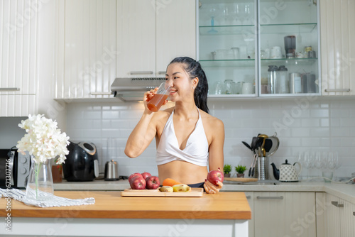 Healthy Asian woman in exercise clothes Is happily cooking a healthy meal in her home kitchen in the morning. Healthy care concept  healthy fruit juice.