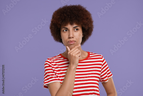 Portrait of thoughtful young woman on purple background
