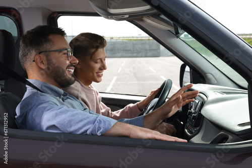 Driving school. Happy student during lesson with driving instructor in car at parking lot