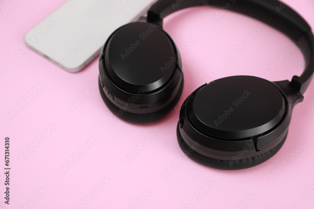 Modern wireless headphones and smartphone on pink background, closeup Modern wireless headphones and smartphone on pink background, closeup
