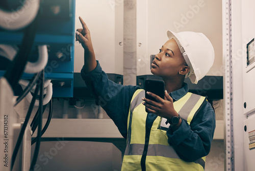 Black woman, engineering technician and phone in control room to connect system, mechanic industry or machine maintenance. Female electrician, mobile technology or check power at electrical generator