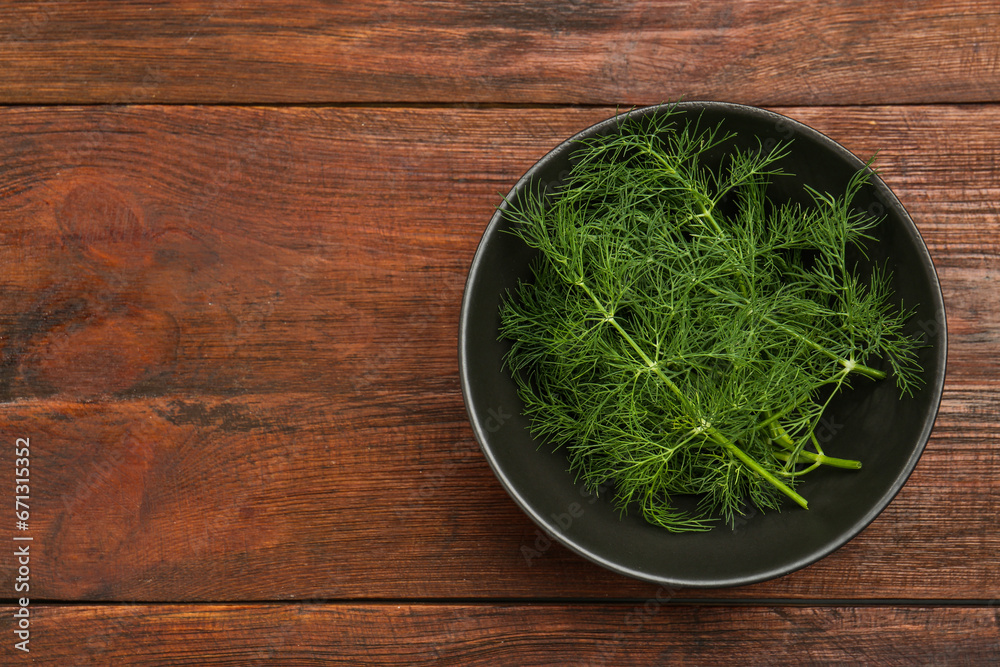 Bowl of fresh green dill on wooden table, top view. Space for text Bowl of fresh green dill on wooden table, top view. Space for text