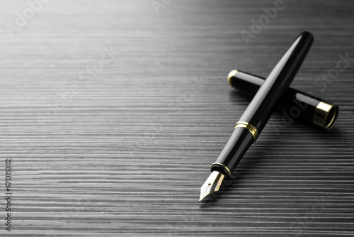 Stylish fountain pen on black wooden table, closeup. Space for text