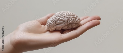 Human brain model in hand on gray background.