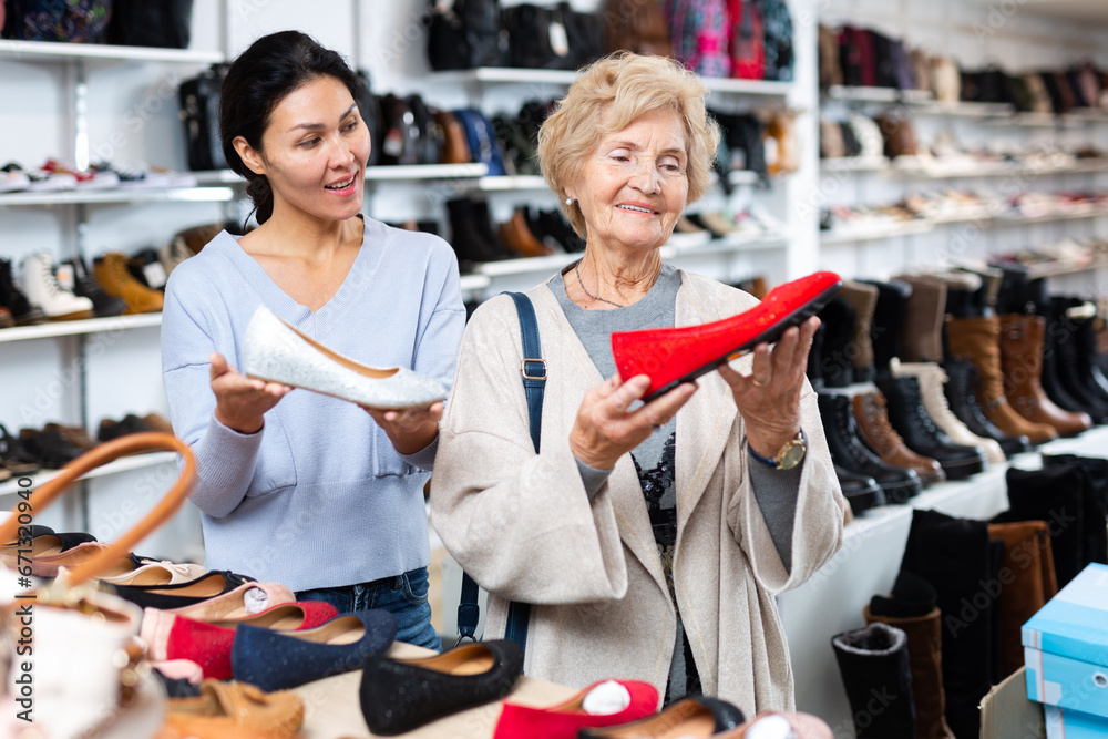 Friendly female sales consultant demonstrates ballet flats to a mature woman customer who came to a shoe store for shopping
