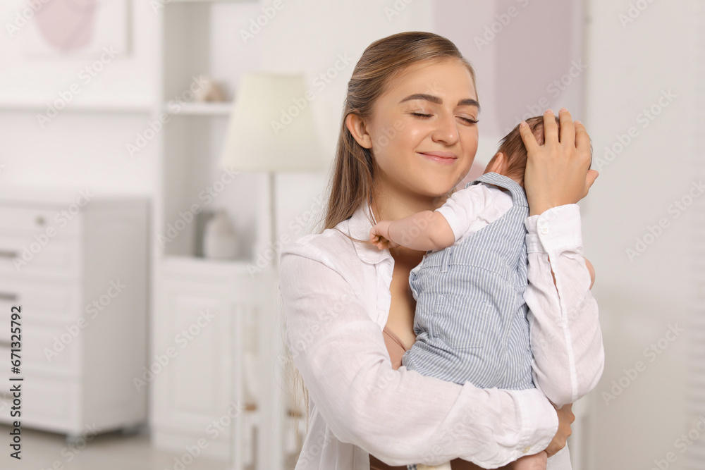 Mother holding her cute newborn baby in child's room, space for text Mother holding her cute newborn baby in child's room, space for text