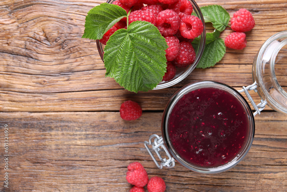 Jar of delicious raspberry jam, fresh berries and green leaves on wooden table, flat lay. Space for text Jar of delicious raspberry jam, fresh berries and green leaves on wooden table, flat lay. Space for text