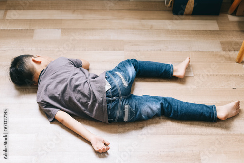 Little boy in casual jeans and t shirt sleeping on wooden floor. Fainted boy photo