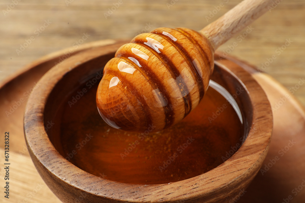Dipper with honey in wooden bowl at table, closeup Dipper with honey in wooden bowl at table, closeup