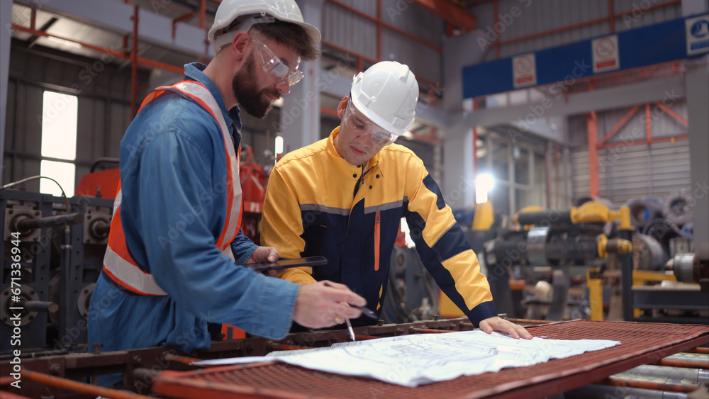 Team of engineers and architects working with blueprint at factory site. It is a massive new facility for making metal sheets as well as a transportation and distribution warehouse. Team of engineers and architects working with blueprint at factory site. It is a massive new facility for making metal sheets as well as a transportation and distribution warehouse.