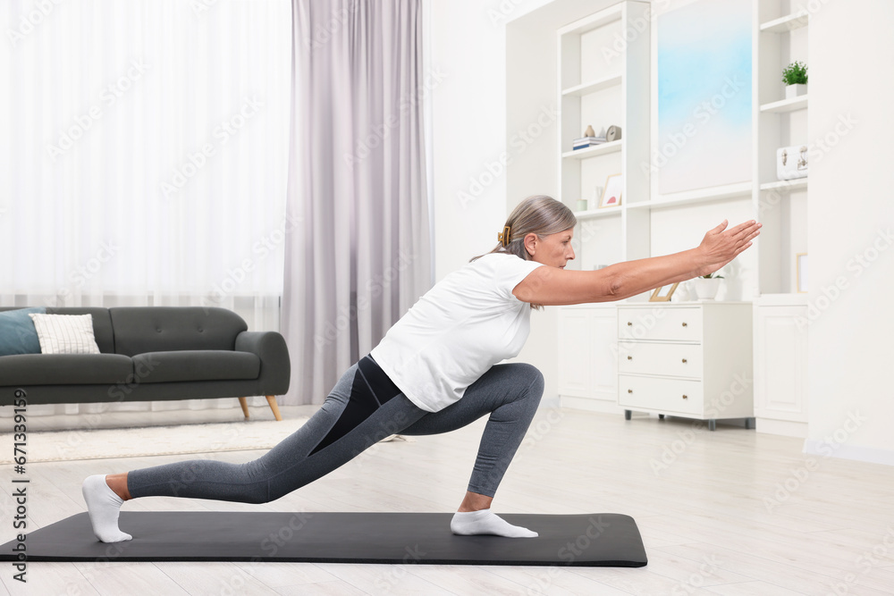 Senior woman practicing yoga on mat at home Senior woman practicing yoga on mat at home