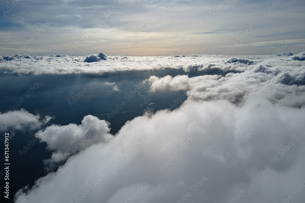 Aerial view from airplane window at high altitude of earth covered with puffy cumulus clouds forming before rainstorm Aerial view from airplane window at high altitude of earth covered with puffy cumulus clouds forming before rainstorm