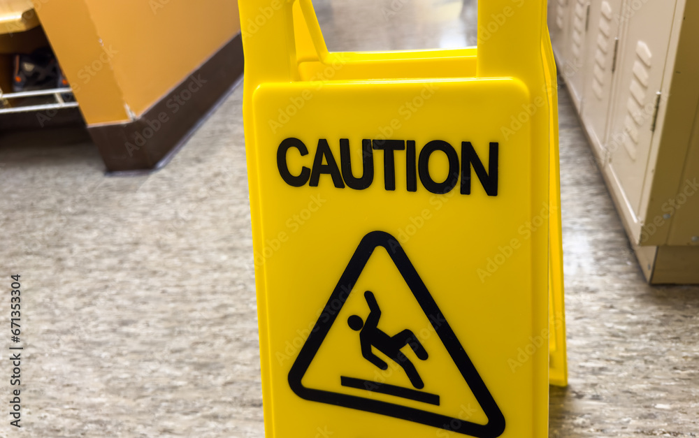 caution sign stands tall against a backdrop of hard hats and heavy
