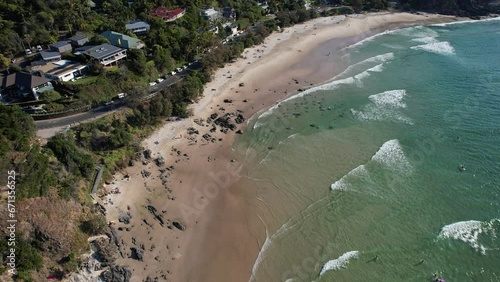 Ocean Waves Splashing Sandy Shore At Little Wategos Beach In NSW, Australia - aerial drone shot photo