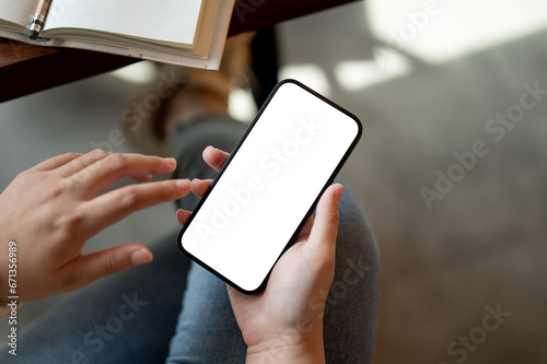 A woman using her smartphone while sitting at a table indoors. A white-screen smartphone mockup.