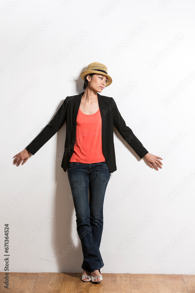 Chinese woman standing in front of wall & looking away